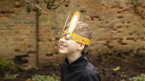 A boy with paper Easter bunny ears over his eyes
